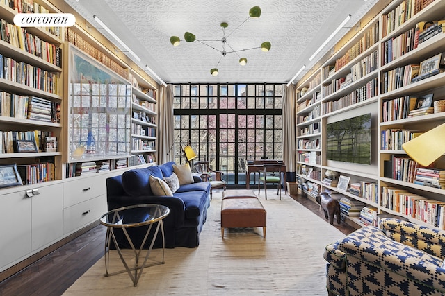 sitting room featuring floor to ceiling windows, hardwood / wood-style floors, a textured ceiling, and bookshelves