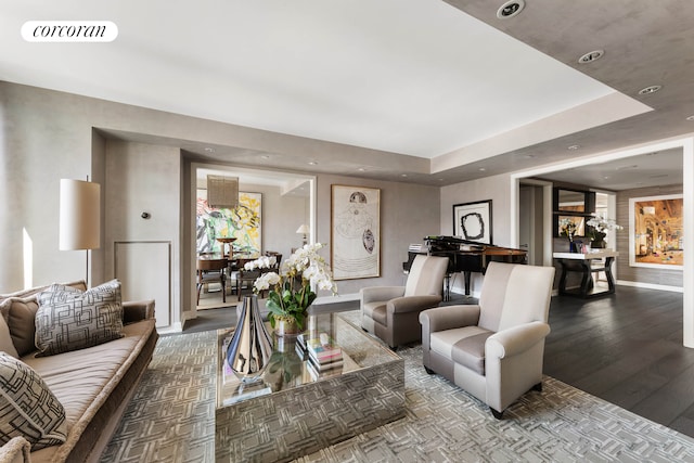living area with a raised ceiling, recessed lighting, baseboards, wood finished floors, and visible vents