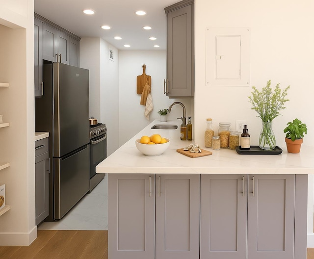 310 E 46th St Unit 18J, New York City, NY 10017 - kitchen with stainless steel appliances, gray cabinetry, electric panel, recessed lighting, and light wood-style floors