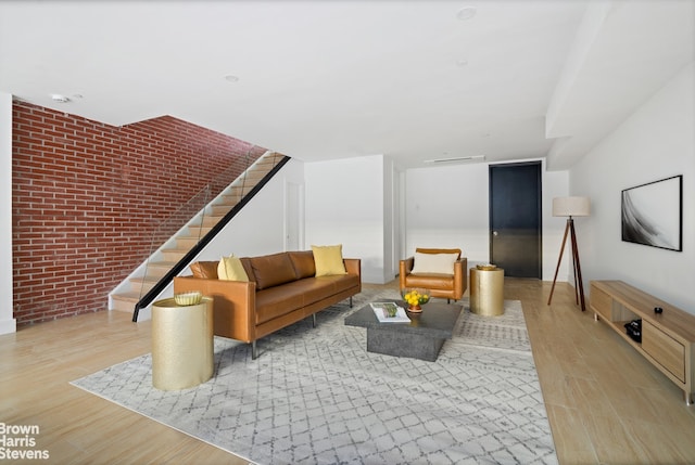 sitting room with wood finished floors, brick wall, and stairway