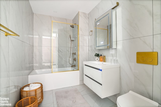 bathroom featuring tile walls, combined bath / shower with glass door, vanity, and toilet