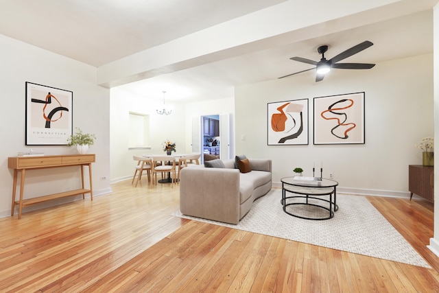 living room with light wood finished floors, a chandelier, a ceiling fan, and baseboards