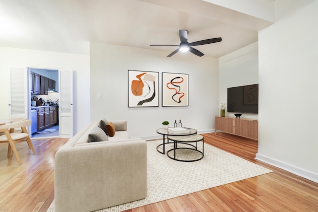 living area featuring light wood-style floors, ceiling fan, and baseboards