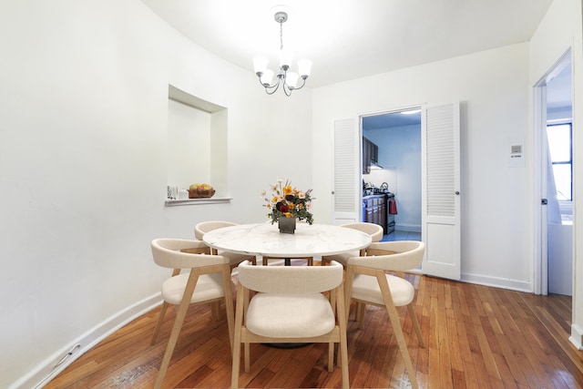 dining area with a chandelier, hardwood / wood-style floors, and baseboards