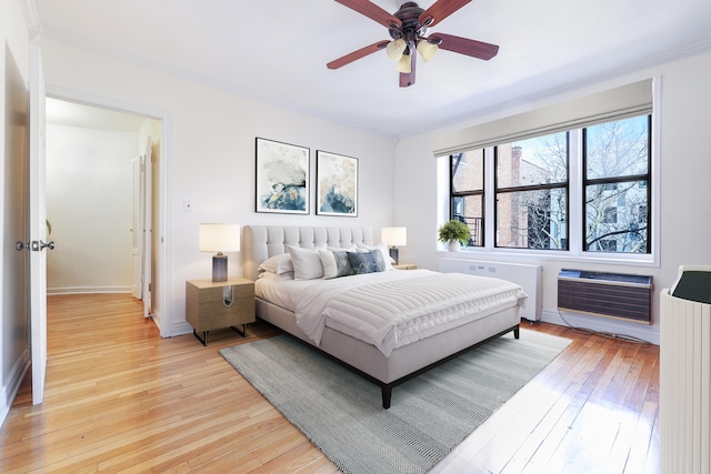 bedroom with light wood-style flooring, radiator, crown molding, heating unit, and baseboards