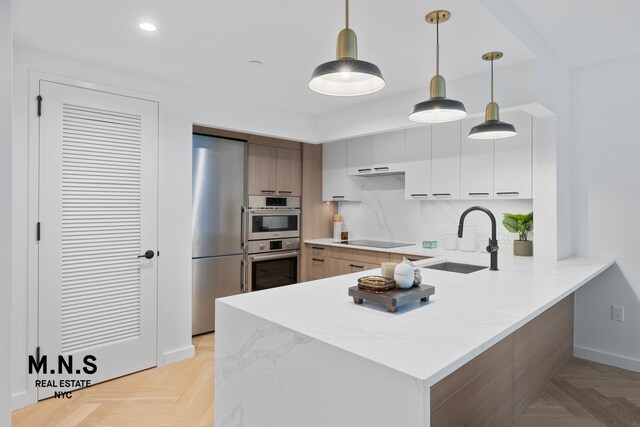 22-54 46th St Unit 704, New York City, NY 11105 - kitchen with a sink, appliances with stainless steel finishes, a peninsula, pendant lighting, and modern cabinets