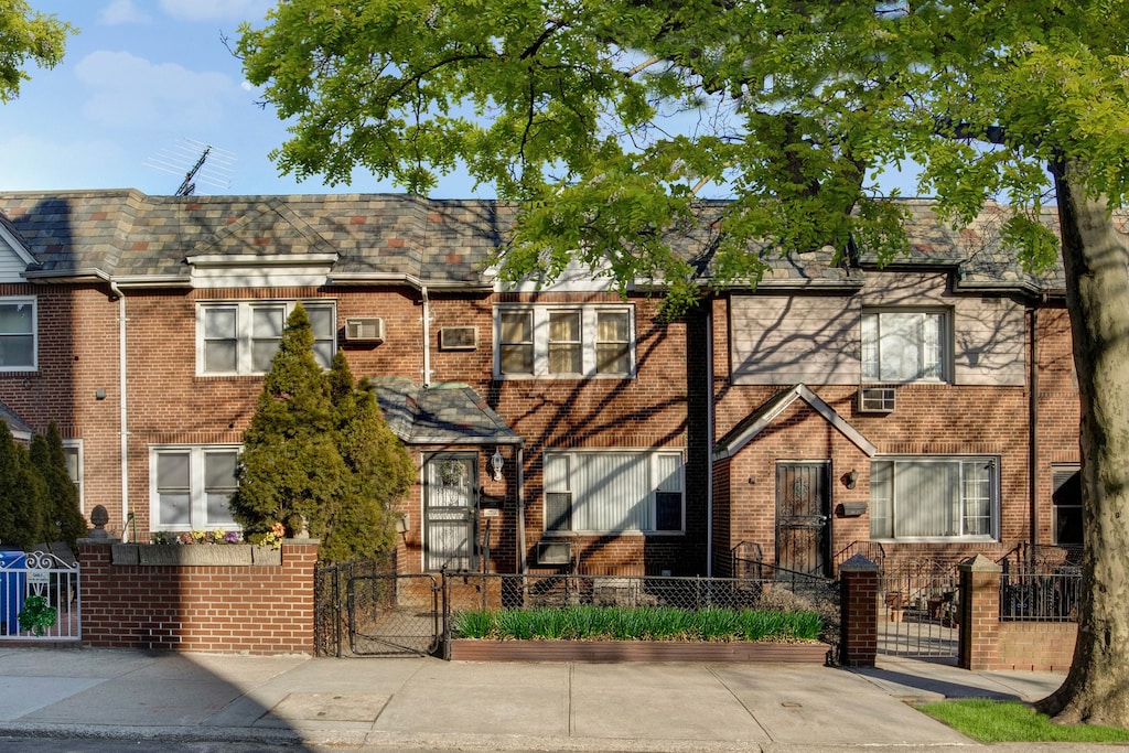 view of property with a gate, a fenced front yard, and brick siding