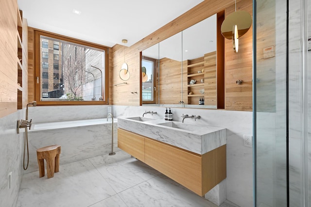 full bath with double vanity, marble finish floor, wood walls, a bath, and a sink