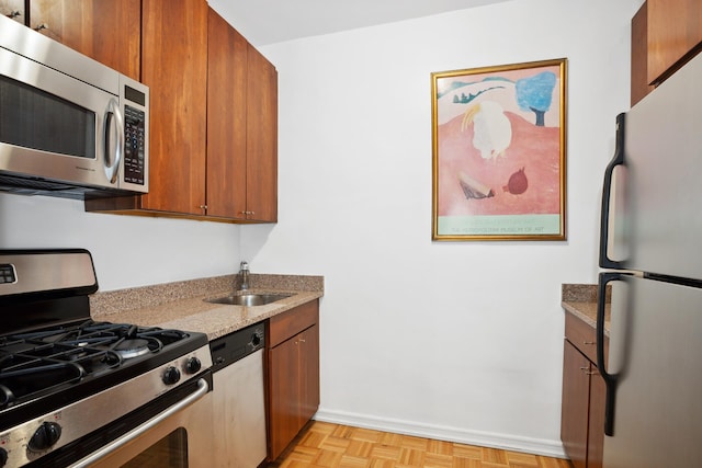 301 E 69th St Unit 15K, New York City, NY 10021 - kitchen with appliances with stainless steel finishes, a sink, baseboards, light stone countertops, and brown cabinetry