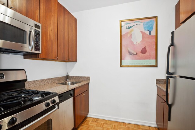 301 E 69th St Unit 15K, New York City, NY 10021 - kitchen with appliances with stainless steel finishes, a sink, baseboards, light stone countertops, and brown cabinetry
