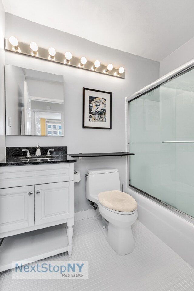 245 E 54th St Unit 22A, New York City, NY 10022 - bathroom featuring toilet, vanity, combined bath / shower with glass door, and tile patterned flooring