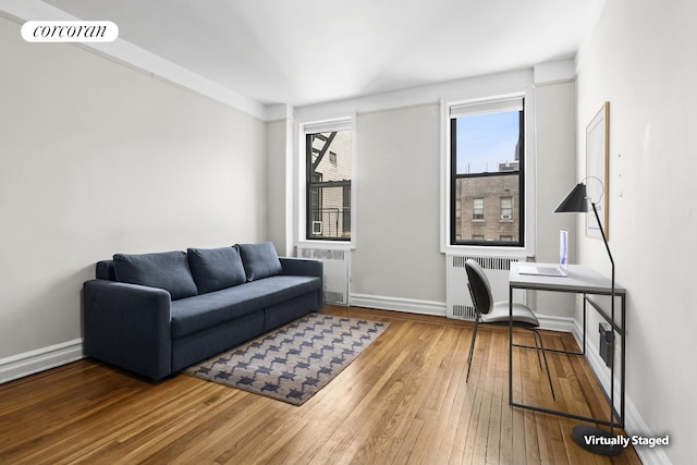 living area featuring radiator, baseboards, and hardwood / wood-style flooring