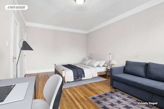 bedroom featuring baseboards, visible vents, ornamental molding, and wood finished floors