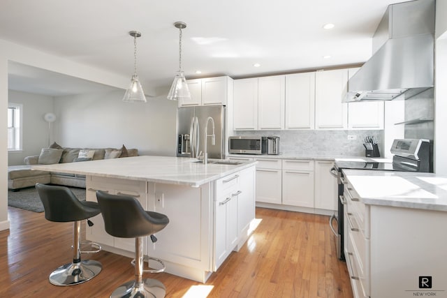 110-12 64th Ave Unit 2-Ab, New York City, NY 11375 - kitchen featuring appliances with stainless steel finishes, wall chimney range hood, backsplash, light stone countertops, and open floor plan