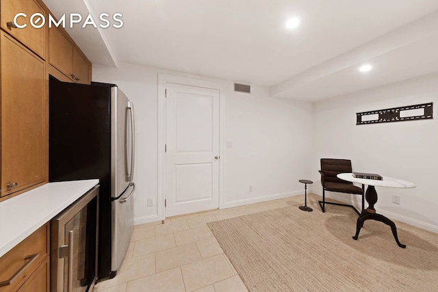 9 W 84th St, New York City, NY 10024 - kitchen with beverage cooler, brown cabinets, freestanding refrigerator, recessed lighting, and light tile patterned flooring