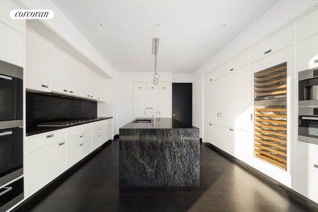 157 W 57th St Unit 56C, New York City, NY 10019 - kitchen featuring black cooktop, white cabinets, dark wood-style floors, visible vents, and a sink