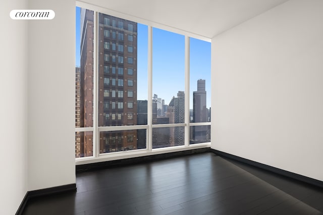157 W 57th St Unit 56C, New York City, NY 10019 - empty room featuring baseboards, expansive windows, dark wood-style floors, and a view of city