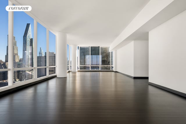 157 W 57th St Unit 56C, New York City, NY 10019 - empty room featuring a city view, baseboards, wood finished floors, and floor to ceiling windows