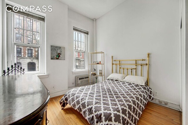 337 E 18th St, New York City, NY 10003 - bedroom with baseboards, wood-type flooring, and a wall mounted air conditioner