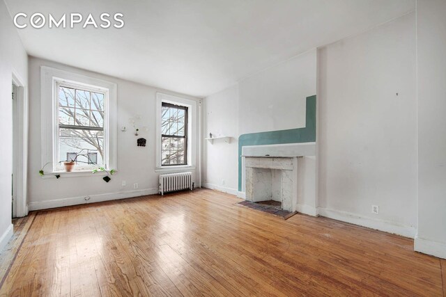 337 E 18th St, New York City, NY 10003 - unfurnished living room with radiator heating unit, baseboards, a fireplace, and wood finished floors