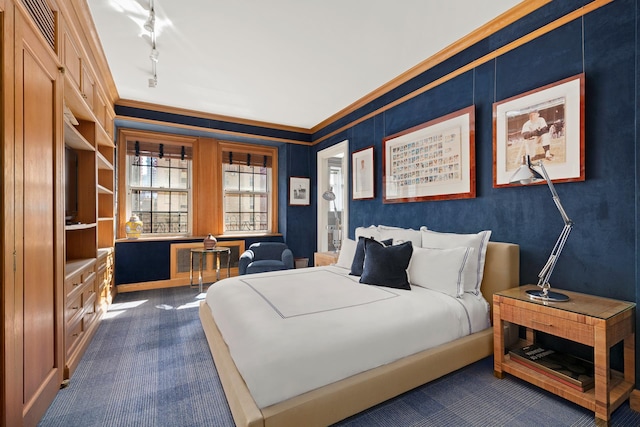 bedroom featuring rail lighting, dark colored carpet, and ornamental molding