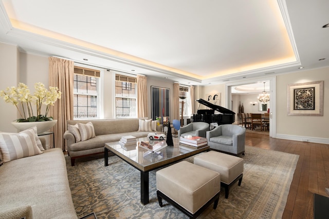 living area with a chandelier, wood-type flooring, a tray ceiling, and baseboards