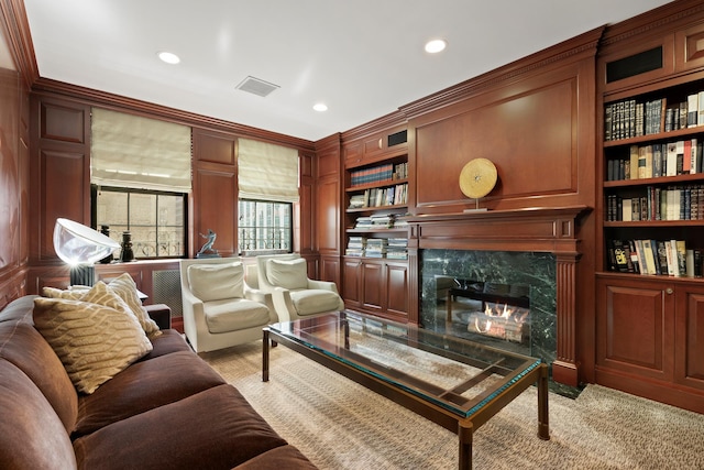 living area with built in features, a decorative wall, crown molding, recessed lighting, and a premium fireplace
