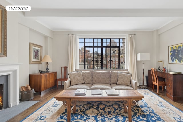 living area featuring wood finished floors, a lit fireplace, and ornamental molding