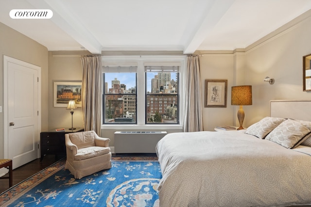 bedroom with beamed ceiling, wood finished floors, and a view of city