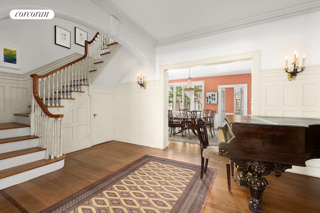 entrance foyer with crown molding, visible vents, a chandelier, stairs, and hardwood / wood-style flooring