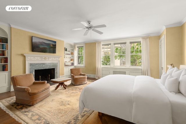 bedroom featuring wood finished floors, a fireplace, ornamental molding, and visible vents