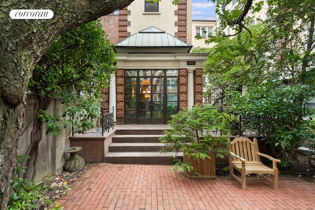 doorway to property with brick siding, french doors, fence, and a patio