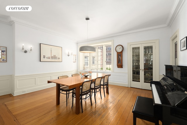 dining space with crown molding, wainscoting, visible vents, and light wood-type flooring