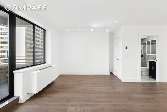 spare room featuring plenty of natural light, wood finished floors, and baseboards