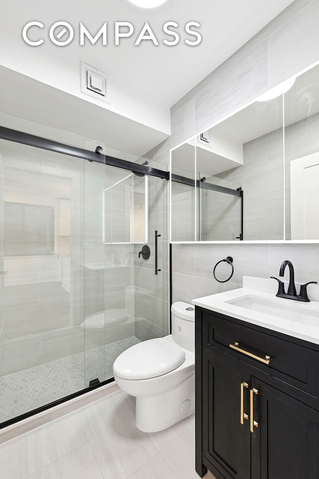 bathroom featuring tile walls, toilet, a shower stall, vanity, and decorative backsplash