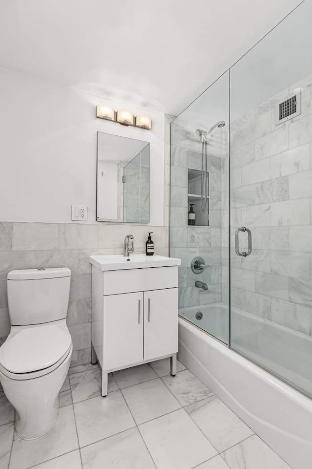 20 E 68th St Unit 5G, New York City, NY 10065 - full bathroom featuring marble finish floors, vanity, bath / shower combo with glass door, toilet, and tile walls