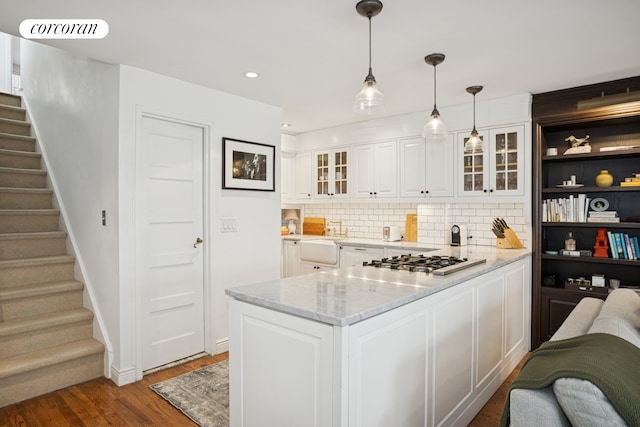 443 W 24th St Unit G, New York City, NY 10011 - kitchen featuring stainless steel gas cooktop, white cabinets, decorative backsplash, glass insert cabinets, and a peninsula