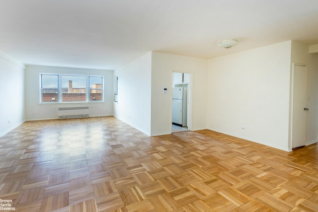 empty room with radiator heating unit and baseboards