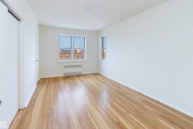 3750 Hudson Manor Ter Unit 6Hw, New York City, NY 10463 - unfurnished bedroom featuring radiator heating unit, light wood-type flooring, baseboards, and a closet