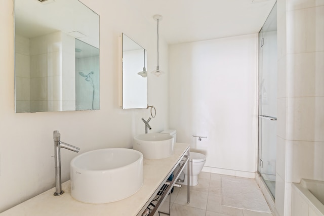 bathroom featuring a sink, toilet, a shower stall, double vanity, and tile patterned flooring