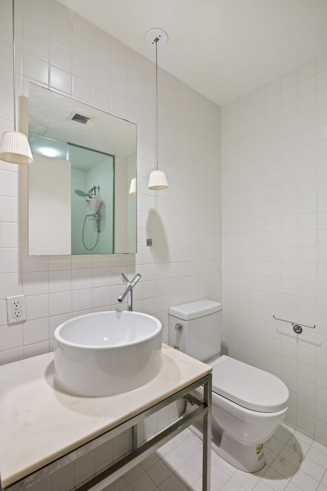 bathroom featuring tile patterned floors, visible vents, tile walls, and a sink