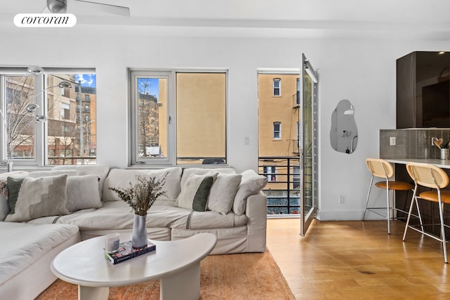 living area featuring wood finished floors, a ceiling fan, and baseboards