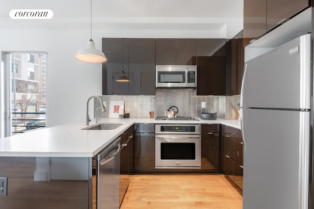 kitchen featuring modern cabinets, a peninsula, stainless steel appliances, and a sink