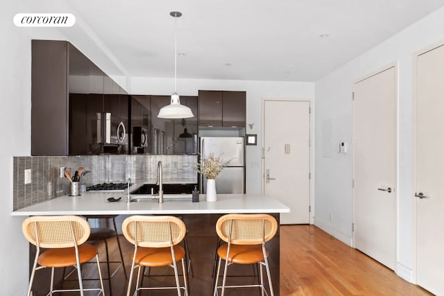 kitchen featuring a sink, decorative backsplash, a peninsula, appliances with stainless steel finishes, and visible vents