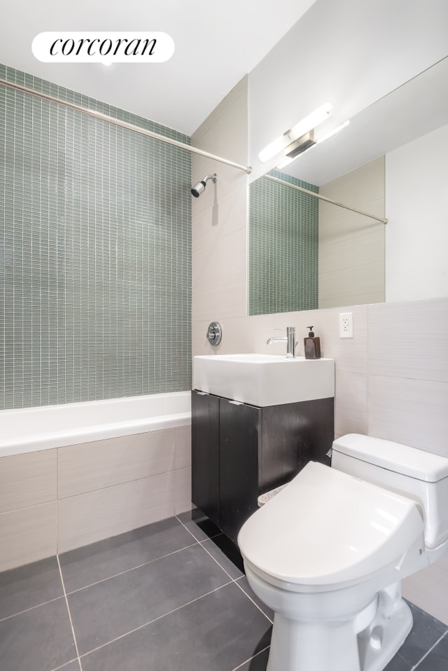 full bath with tile patterned floors, shower / washtub combination, toilet, vanity, and tile walls