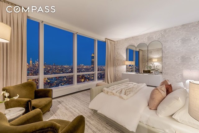 bedroom featuring wallpapered walls, wood finished floors, and a city view