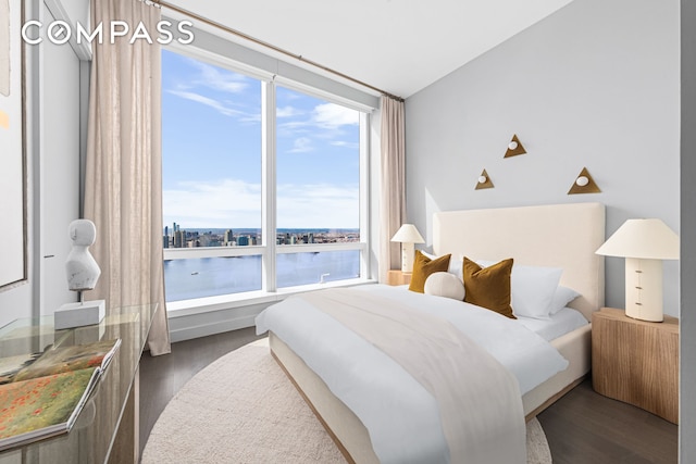 bedroom featuring dark wood-type flooring and a water view