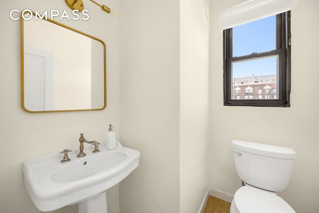 1049 Park Ave Ph, Ph, New York City, NY 10028 - half bathroom with toilet, a sink, wood finished floors, and baseboards