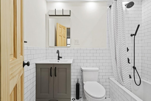 bathroom featuring vanity, toilet, a wainscoted wall, tiled shower / bath, and tile walls