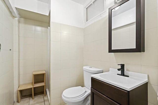 bathroom featuring tile walls, tile patterned floors, vanity, toilet, and tiled shower